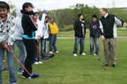 The assistant golf pro goes over the basic elements of the swing with Lakota (Sioux) students.