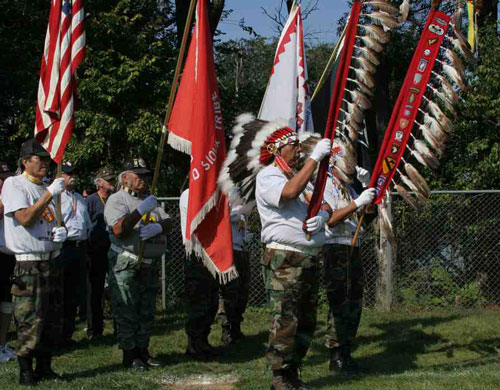 Veterans at St. Joseph's powwow bearing flags and Eagle Staf