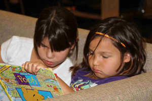 Native American girls read a book in their home.